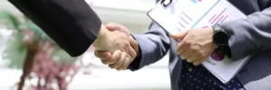 Businessmen shake hands with advertising analytics charts